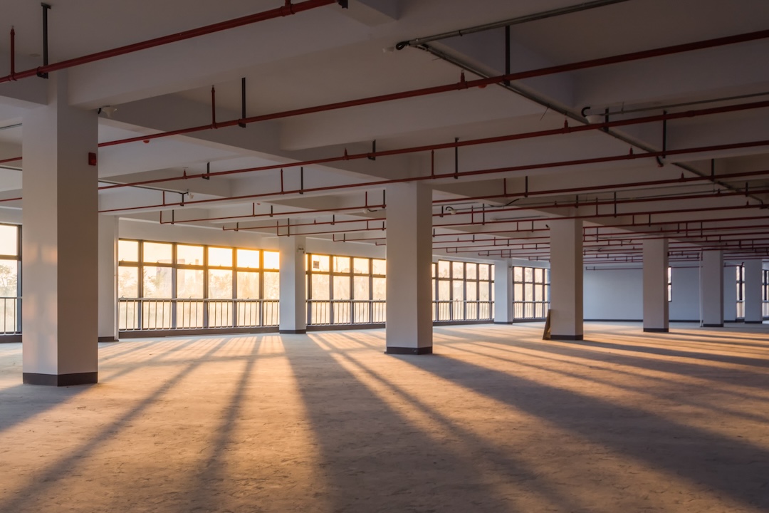 At sunset, orange light pours in through windows in a large empty building. 