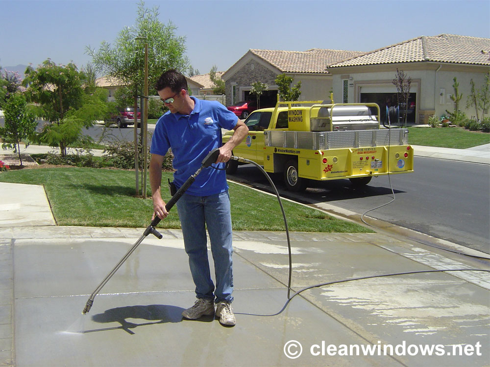 A Brite and Clean Technician uses a pressure washer to clean a driveway. 